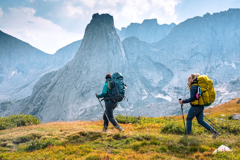 Two women walk along a trail with the Cirque of the Towers in Wyoming in the background