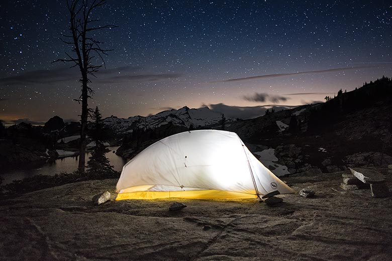 An ultralight tent is lit up at night.