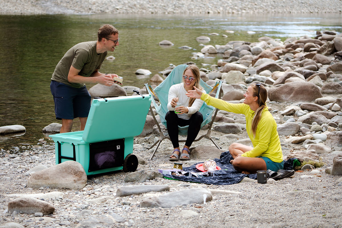 A happy group of friends picnics by the side of the river.