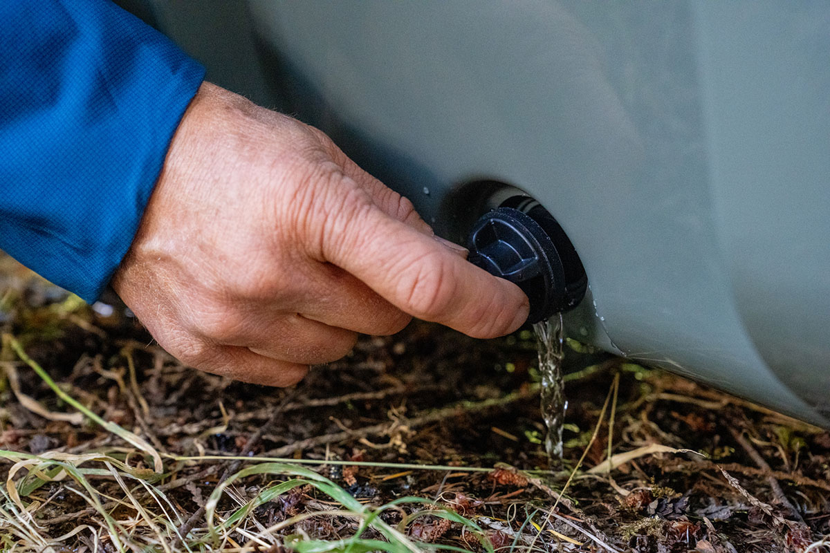 A cooler's drainage system is opened and water is flowing out. 