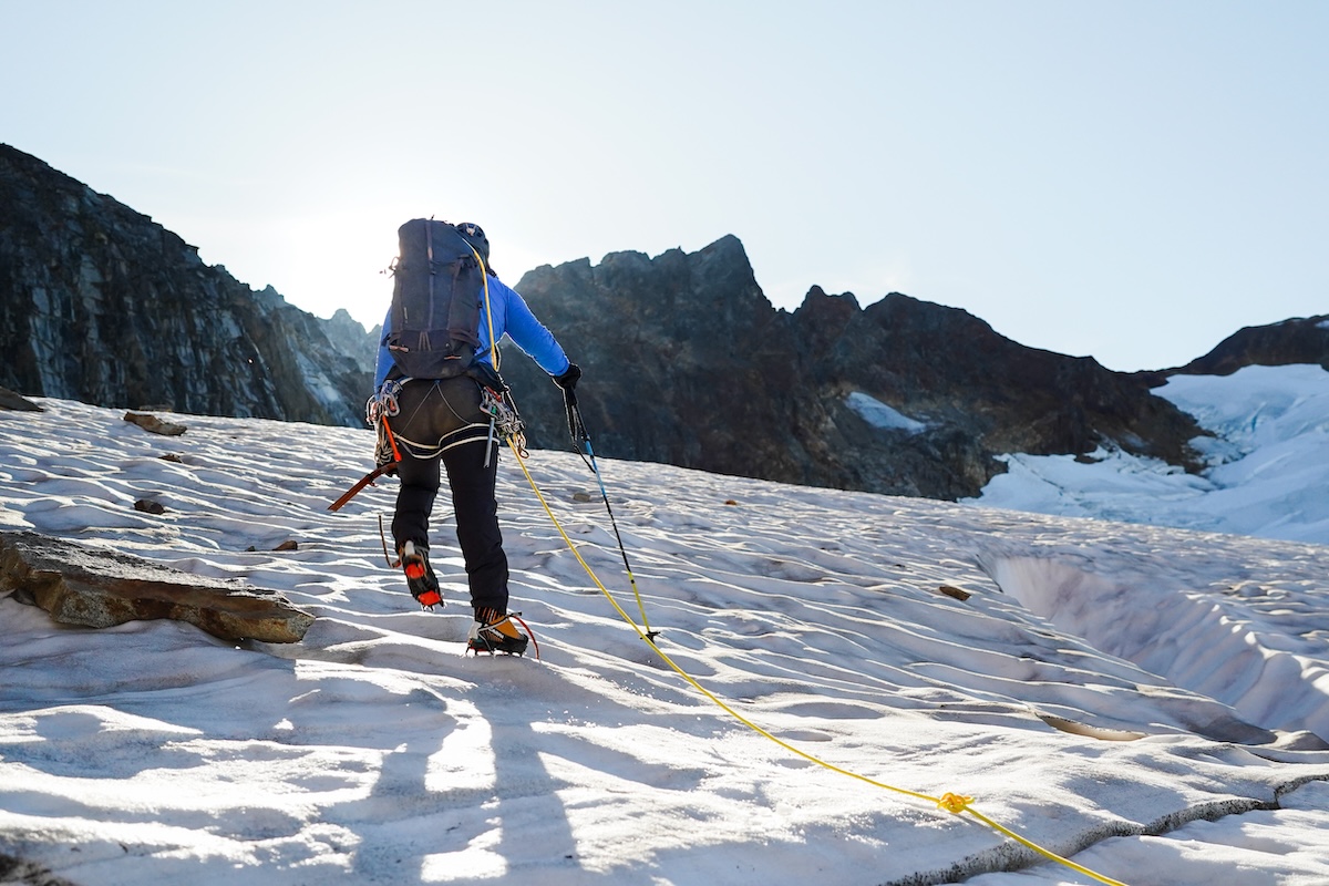 A mountaineer on a rope team summits Sahale Peak