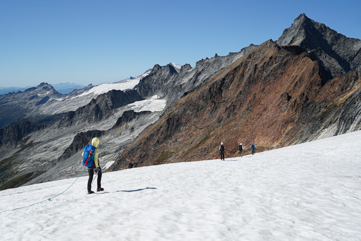 A climber on a rope traverses an ice field in the Cascade mountains.