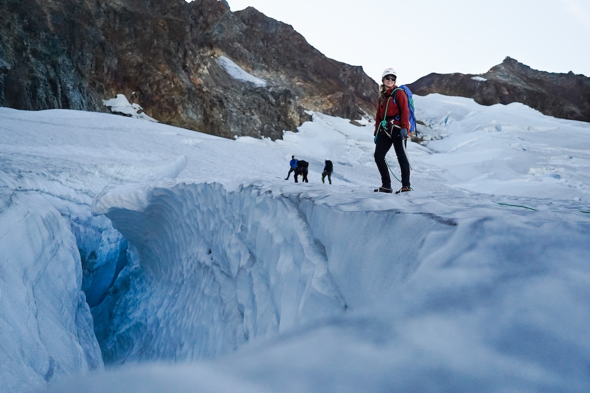 A woman travels across a glacier with her dogs. 