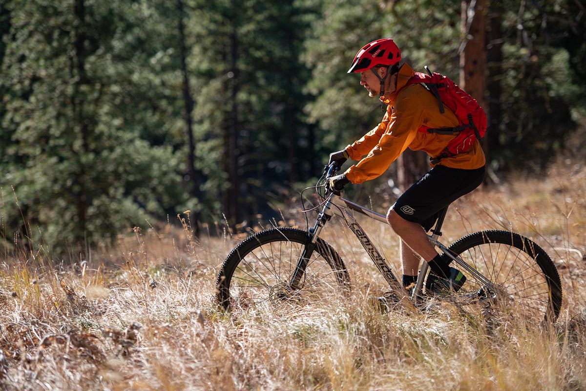 A man rides a mountain bike across a golden mountain field.